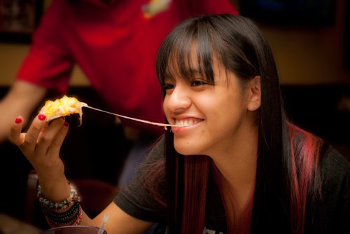 Girl enjoying a cheesy slice of pizza